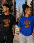 Two people wearing Knicks-themed t-shirts on a city street with the Empire State Building in the background.